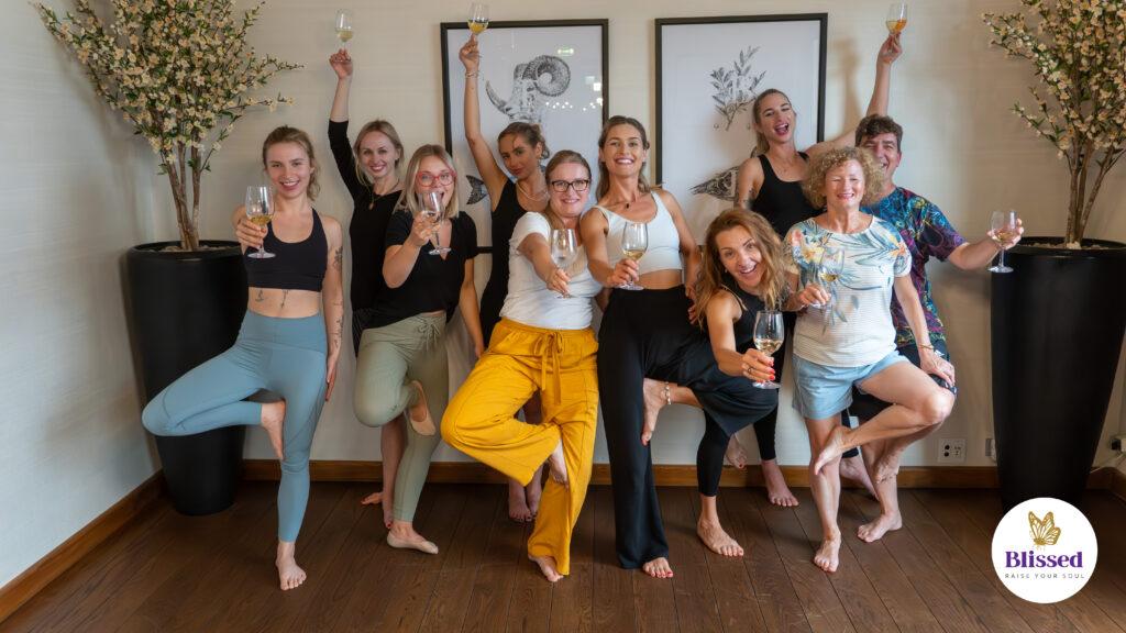 Grupa osób pozujących do zdjęcia po warsztacie Wine Yoga.